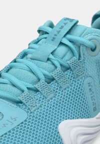 Αθλητικό παπούτσι ανοιχτού γαλάζιου χρώματος με πλέγμα στο πάνω μέρος, διακοσμητικές υφές, ενισχυμένες τρύπες για τα κορδόνια και ελαφριά σόλα με εμφανές λογότυπο.