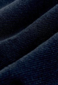 Námořnická modrá texturovaná látka s vertikálními pruhy, která má jemný, mírně chlupatý povrch, jenž zvyšuje její hmatovou kvalitu.