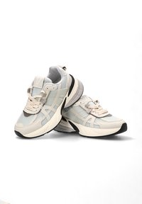Zapatillas ligeras en malla beige y gris con un acabado texturizado. Presentan una puntera redondeada, un cuello acolchado y una suela negra en contraste.