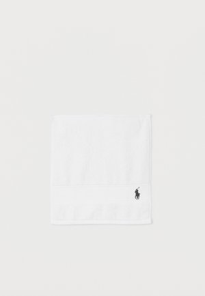 Serviette blanche pliée avec un petit logo noir brodé d'un joueur de polo à cheval dans le coin inférieur droit.
