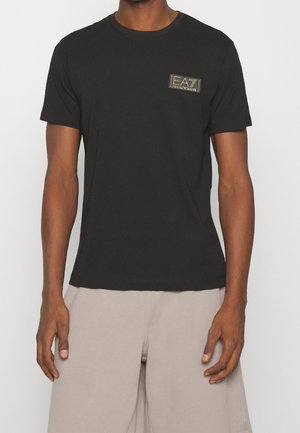 Černé tričko s krátkým rukávem vyrobené z bavlny, s malou nášivkou loga EA7 na levé horní straně. Klasický kulatý výstřih.