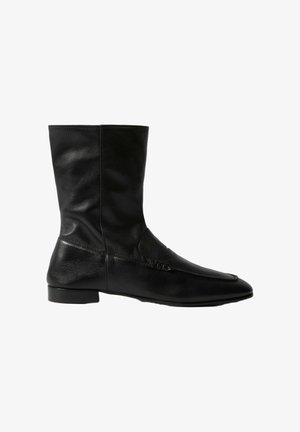 Botas de cuero negro hasta el tobillo con punta afilada, acabado liso, detalles de costura en el lateral y un tacón bajo y cuadrado.