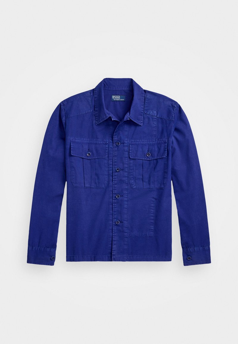 Blå långärmad skjorta i bomull med två frampockets. Har en knäppning framtill och en klassisk krage. Slät textur.