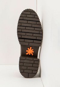 Black rubber shoe sole with textured traction pattern and prominent orange star logo at the center. Flat, oval shape with reinforced edges.