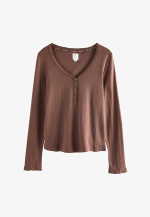 Langärmliges Shirt in Rostfarbe, mit V-Ausschnitt, verdeckter Knopfleiste mit vier Knöpfen, gerippter Textur und ausgefransten Saumdetails.