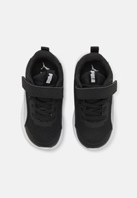 Baskets en maille noires avec une sangle Velcro et des lacets, dotées de semelles blanches et d'un logo sur la languette, conçues pour le confort et le soutien.