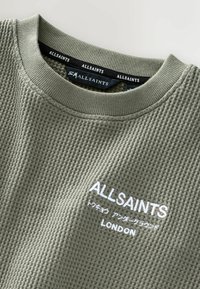 Maglione texture verde oliva con colletto rotondo, che presenta "ALLSAINTS" e "LONDON" ricamati in bianco sul fronte.