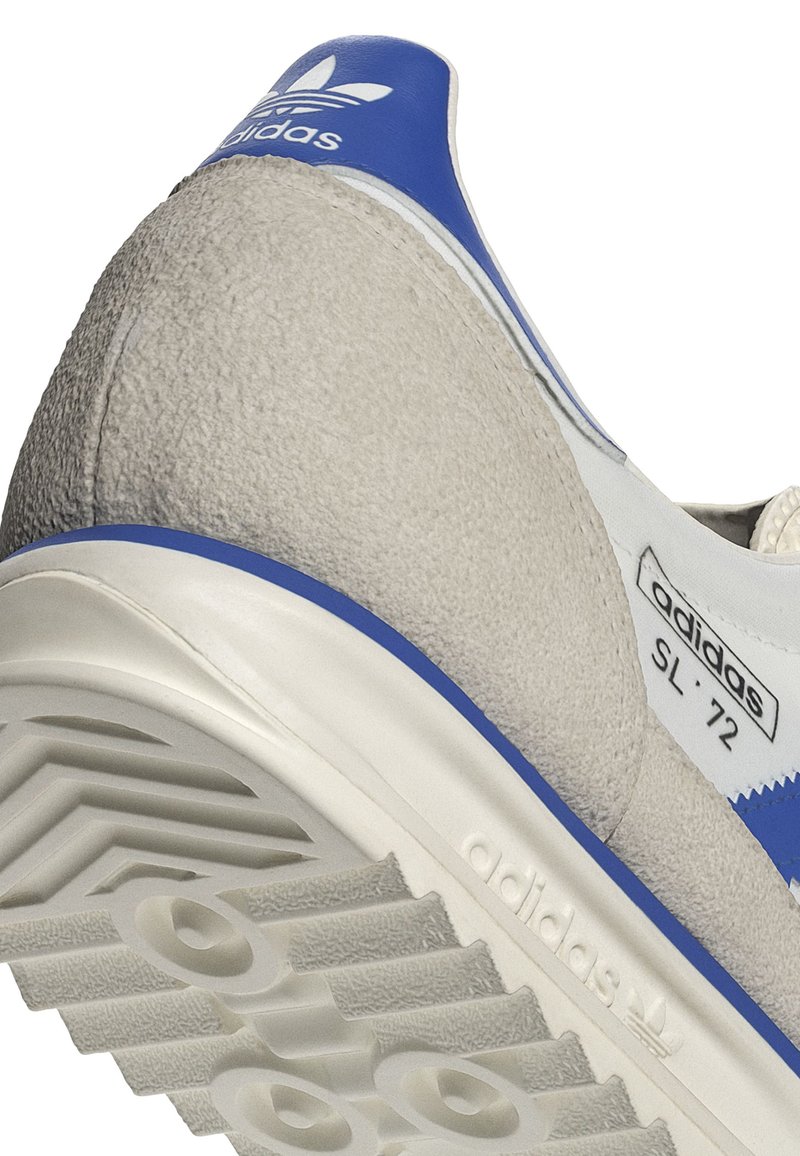Sneakers Adidas SL '72 z szarym zamszowym wierzchem, niebieskimi akcentami, teksturowaną gumową podeszwą oraz logo na pięcie i boku.