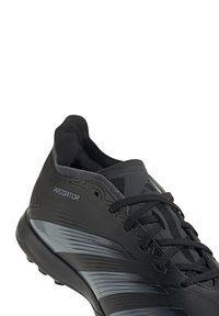 Black athletic shoe with textured synthetic upper, curved design, grey stripe accents, and black laces. Lightweight sole for agility.