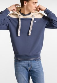 Sudadera azul marino con un panel superior beige, cordones con la marca "Harmont & Blaine" y franjas contrastantes en los puños y el dobladillo. Material de mezcla de algodón.