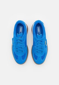 Blaue Sportschuhe mit Obermaterial aus Wildleder und Mesh, runder Zehenpartie, Schnürdesign und einer Laufsohle aus Kautschuk; geprägtes Logo an der Seite.