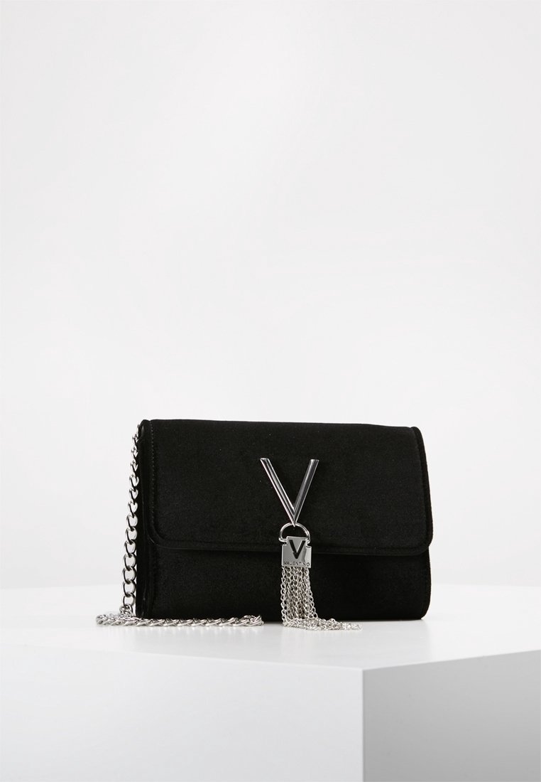 Black suede clutch with silver chain strap, silver "V" logo, and hanging silver chain tassel on white surface against a plain background.