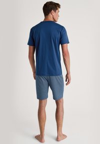 Blauwe katoenen T-shirt voor mannen en blauw patroon korte broek met een geometrisch ontwerp. Beide artikelen hebben korte mouwen en een relaxte pasvorm.