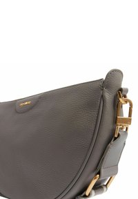 Graue Leder-Schultertasche mit geschwungener Form, strukturierter Oberfläche, goldfarbenen Metallakzenten und abnehmbarem Riemen. Mit einem Logo in der Nähe des oberen Bereichs.