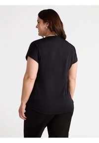 Czarny top z krótkim rękawem, wykonany z gładkiego materiału, z zaokrąglonym dołem i luźnym krojem. Widok z tyłu pokazuje prosty, czysty design bez ozdób.