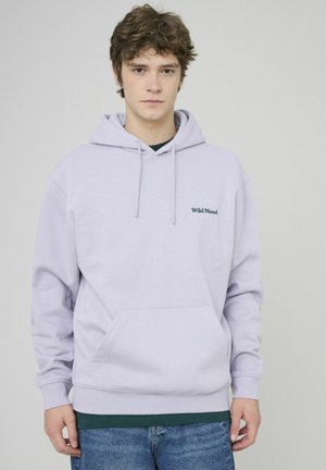 Hoodie violet clair en tissu doux, avec une poche avant, des cordons de serrage, et le texte "Wild Mood" en bleu foncé sur la poitrine.