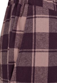 Plaid fabric in shades of mauve and dark purple, featuring a textured finish. Visible seam details and pocket area.