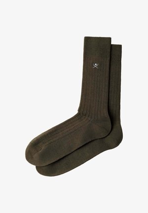 Par de calcetines verdes oscuros acanalados hasta el tobillo con un pequeño logo blanco de espadas cruzadas y casco cerca del puño superior.