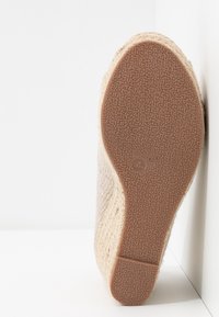 Semelle d'espadrille beige compensée avec semelle extérieure en caoutchouc brun texturé et indication de taille 4, présentée debout sur fond blanc.