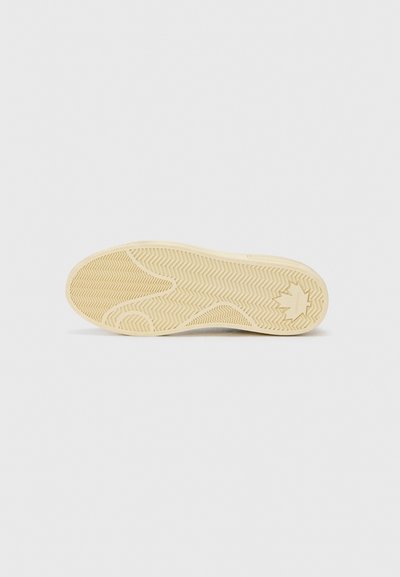 Suela de zapato de color marrón claro, material de goma, patrón de espiga y un detalle de logo en el talón, con un diseño de agarre texturizado.
