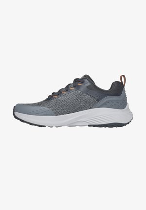 Grauer Sportschuh mit einem atmungsaktiven Mesh-Obermaterial, strukturierten Akzenten, weißer Zwischensohle und Gummisohle mit einem Grip-Muster.