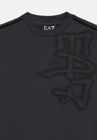 Mørk grå T-skjorte laget av bomull, med en subtilt teksturert EA7-logo i en litt mørkere nyanse foran, rund halsdesign.