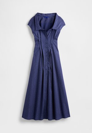Robe bleu marine avec col court structuré, boutonnée devant et plis. Présente des pois blancs et une jupe évasée.