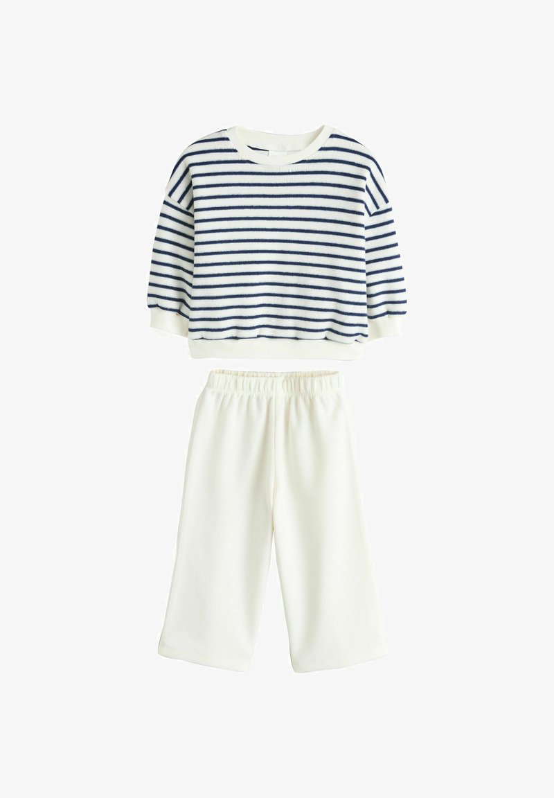 Kinderoutfit met een marineblauw-wit gestreept shirt met lange mouwen en witte wijde broek met elastische tailleband op een witte achtergrond.