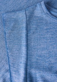 Tela azul claro con un patrón texturizado, acabado suave y escote redondo. Presenta costuras laterales para un ajuste entallado.