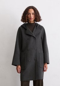 Dunkelgrauer Wollmantel mit Kapuze, doppelt gefüttertem Design, zwei vorderen Taschen und übergroßen Ärmeln für einen entspannten Sitz.