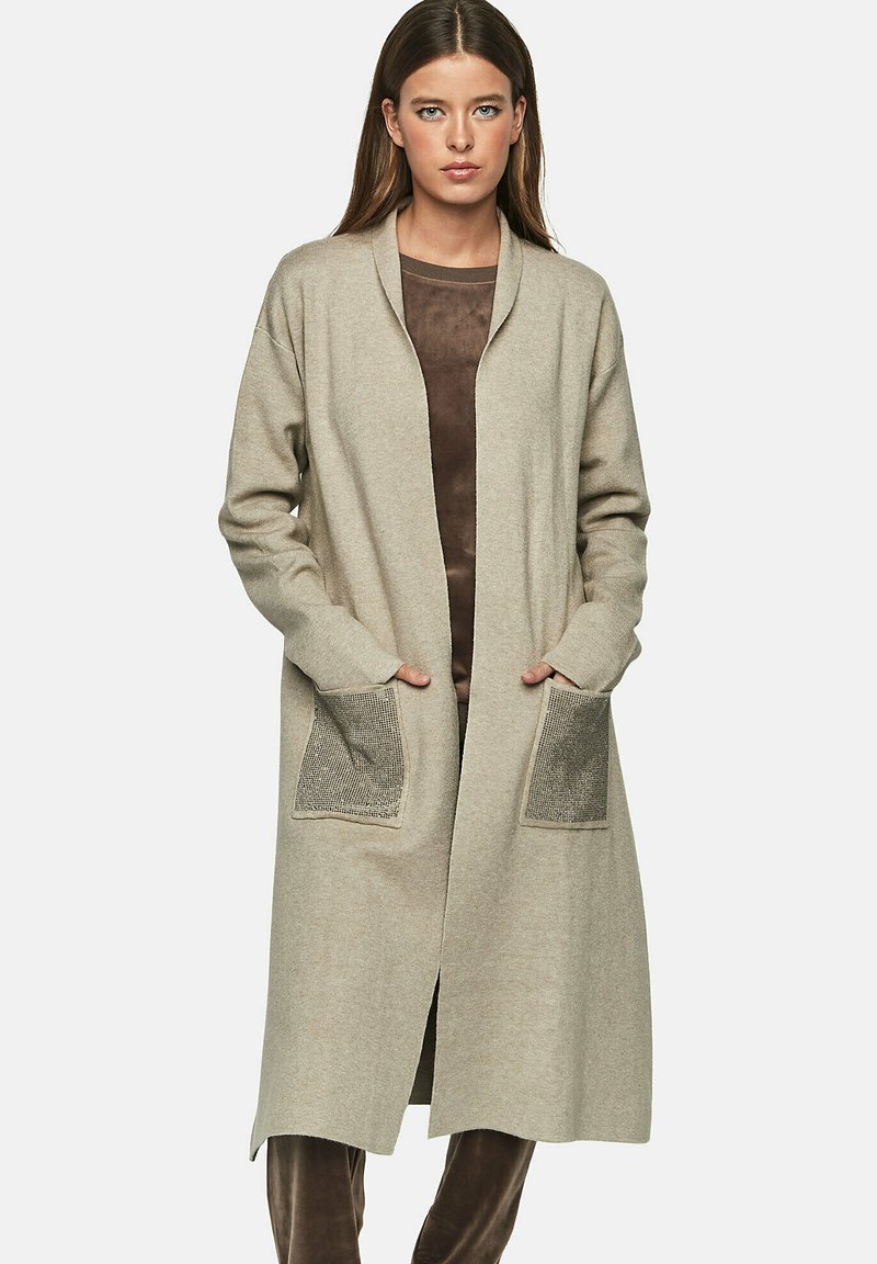 Knielange beige cardigan van zacht materiaal, met een open voorkant, lange mouwen en twee geweven zakken.