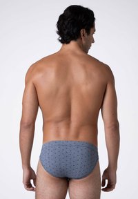 Slip da bagno grigi con motivo a pois, caratterizzati da una vestibilità aderente e un tessuto liscio, mostrati di spalle su un modello.