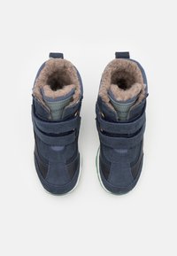 Blå mocka hög-toppskor med foder i päls, med dubbla Velcro-remmar, texturerade accenter och en grön gummisul. Visad från ovan.