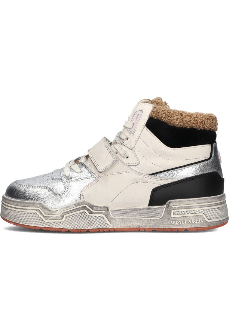 Sneakers typu high-top z metalowym czubkiem w kolorze srebrnym, białą skórzaną cholewką, czarnymi akcentami oraz beżowym futerkiem na kołnierzu. Teksturowana gumowa podeszwa z logo.