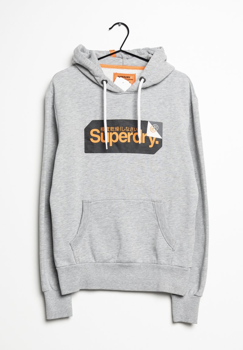 Sweat à capuche Superdry gris clair avec poche kangourou, cordons blancs et logo orange et noir sur la poitrine, suspendu sur un cintre noir.