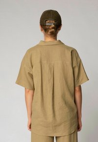 Olivgrünes Kurzarmhemd aus leichtem Stoff mit kleinem Kragen, lässiger Passform und Rückenfalte.
