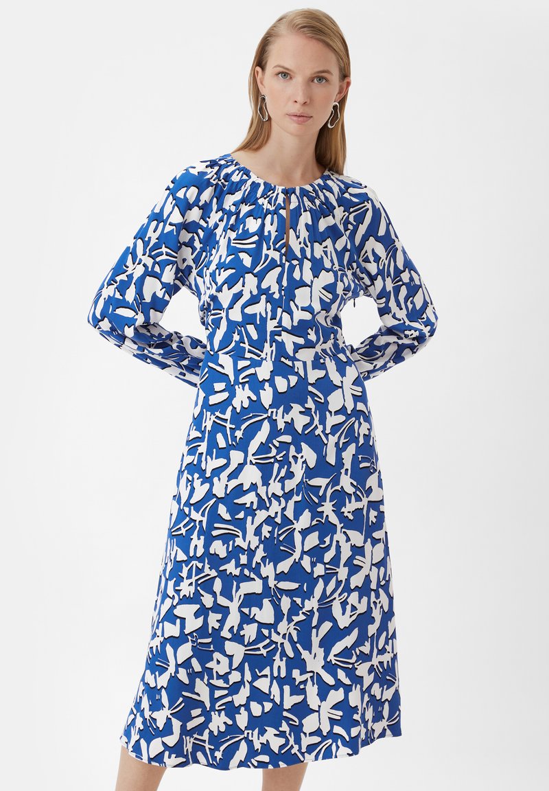 Blau-weißer, blütenmusterter Kleid mit langen Ärmeln, gerafftem Ausschnitt und einem Schlüssellochdetail. Glattes Material, knielanges Design.