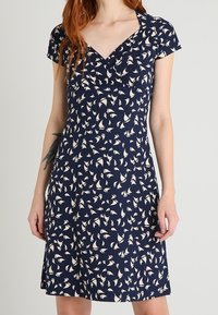 Navy blue dress with short sleeves, featuring a white sailboat pattern. V-neck design and relaxed fit, with a smooth, lightweight fabric.
