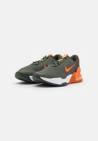 Nike lenkkarit oliivinvihreinä oransseilla yksityiskohdilla, verkkopinta, pehmeä pohja ja teksturoidut kuviot sivuilla ja kielessä.