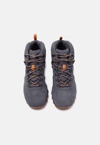 Ζευγάρι σκούρων γκρι ορειβατικών μποτών με κορδόνια και υφασμάτινους βρόχους σε πορτοκαλί τόνους, σε θέαση από πάνω σε λευκό φόντο.