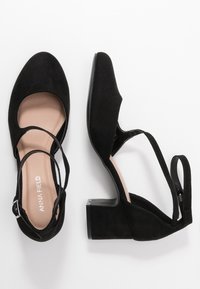 Zapatos de tacón de ante negro con correas para el tobillo y punta redonda, que cuentan con un tacón grueso y un forro interior ligero. Marca: Anna Field.