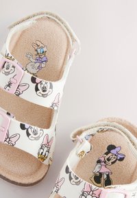 Sandales pour enfants avec tige synthétique blanche, boucles roses, illustrées des personnages Disney Minnie et Daisy, semelle intérieure marron texturée.