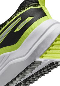 Black and neon green running shoe with a textured upper, padded collar, and a white midsole. Features a patterned rubber outsole for grip.