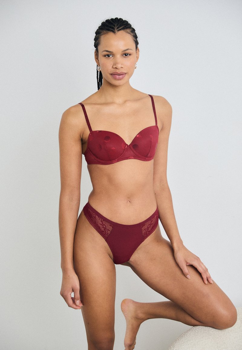Burgundy bra and high-waisted brief set featuring a lace detail on the sides, soft cups, and adjustable straps, made from a smooth material.