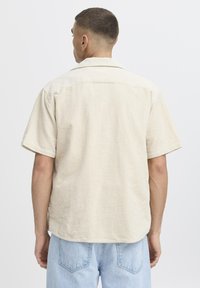 Short-sleeve shirt in light beige corduroy, featuring a point collar and a relaxed fit, with a textured surface and back yoke detail.
