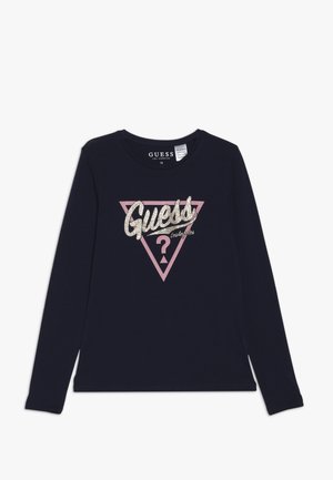 Granatowa koszula z długim rękawem ozdobiona różowym trójkątnym motywem z napisem "Guess" wykonanym brokatem oraz znakiem zapytania w centrum. Miękki materiał, okrągły dekolt.