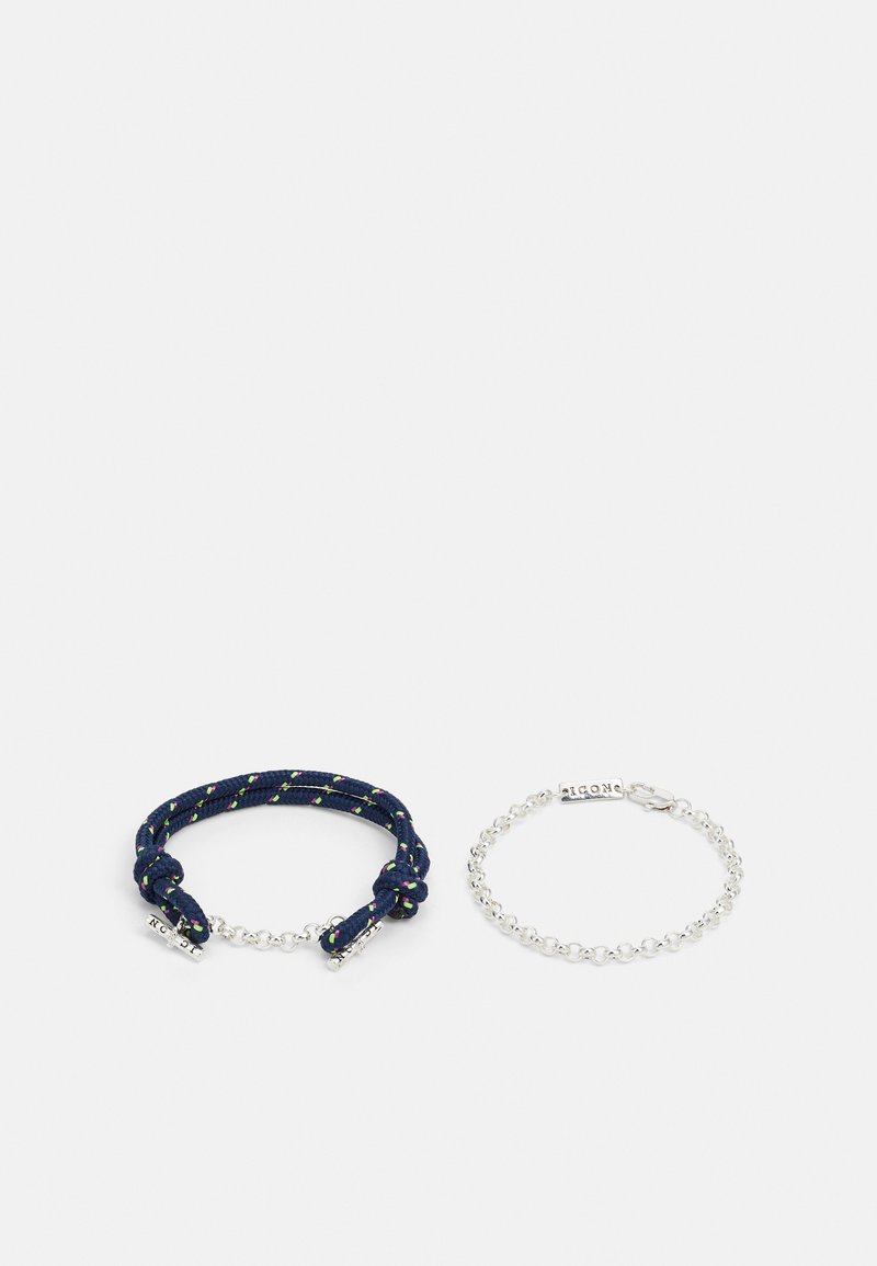 Deux bracelets : un bracelet en corde tressée bleu marine avec des accents verts et un bracelet en chaîne argentée avec une fermeture à clip. Les deux présentent des designs simples.