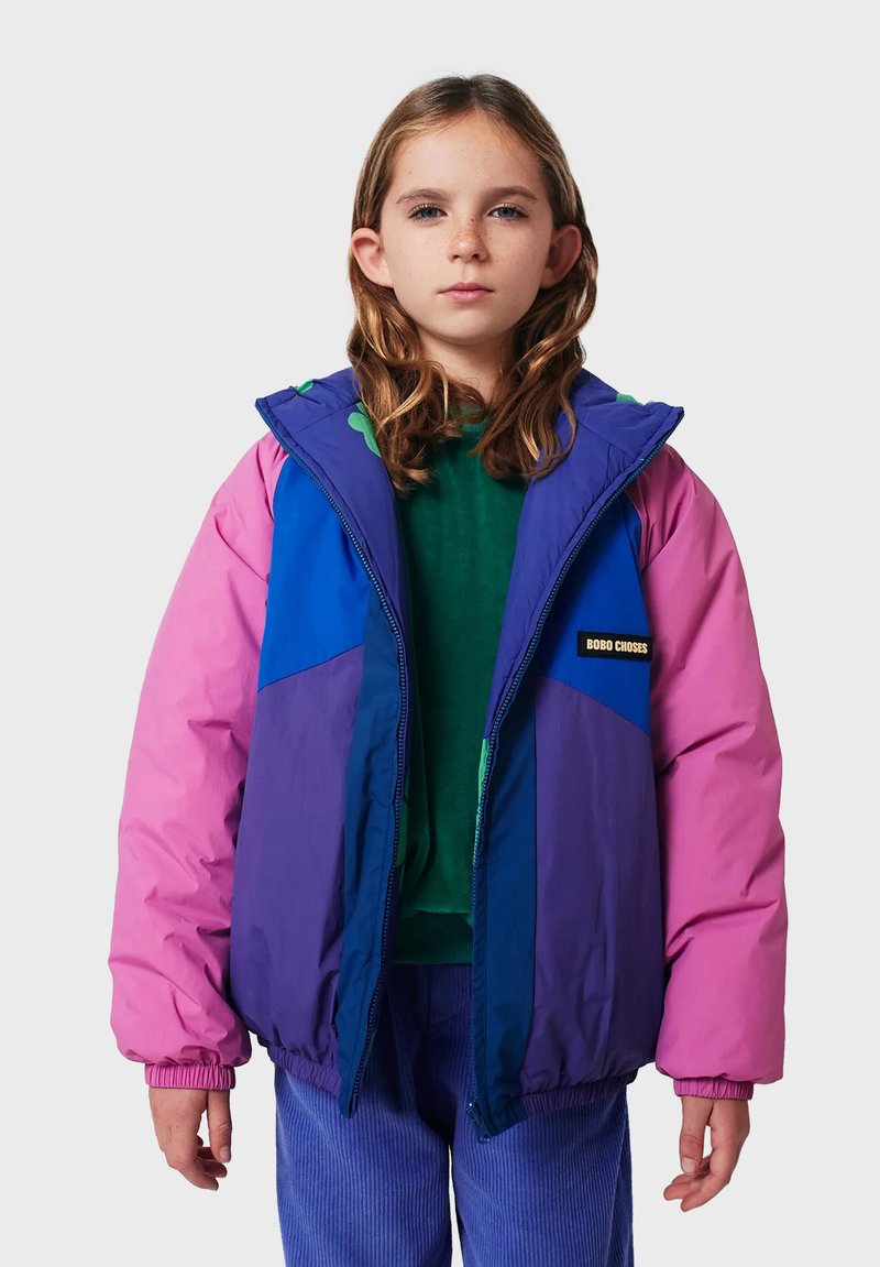 Colorful puffy jacket featuring pink, blue, and purple panels. Zipper closure, elastic cuffs, with a logo patch on the chest. Suitable for cooler weather.
