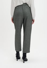 Spodnie w szaro-czarny wzór w ząbki, o luźnym kroju, z elastycznym pasem i dwoma kieszeniami, zestawione z czarnymi botkami na obcasie.