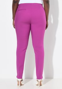 Pantaloni attillati a vita alta in vivace tessuto magenta con una texture liscia. Presentano una tasca posteriore singola e un design a gamba affusolata.